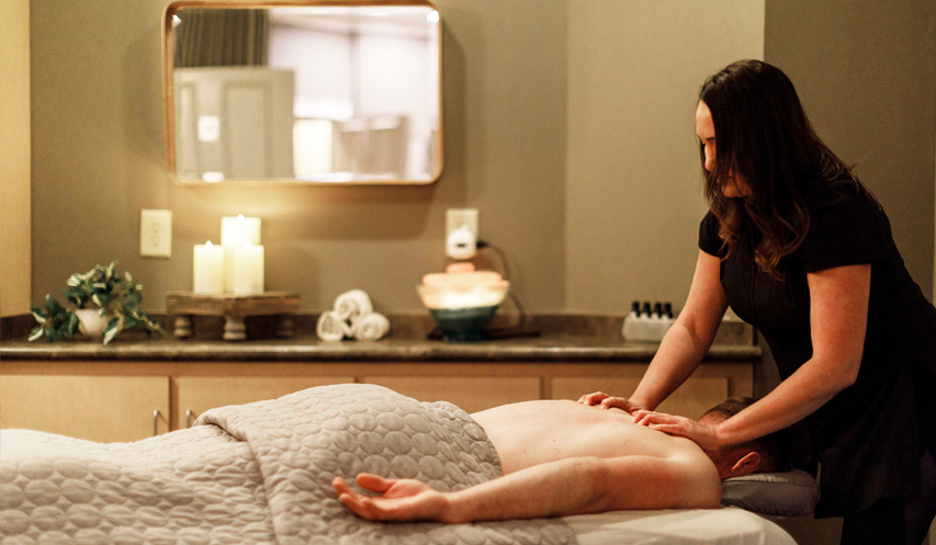 - The Renaissance Day Spa & Alternative Wellness, Fayetteville NC A massage therapist gives a back massage to a person lying face down on a table in a spa room with candles and towels in the background. - The Renaissance Day Spa & Alternative Wellness, Fayetteville NC